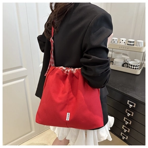 Detail view of red canvas drawstring tote bag with red and white gingham trim detail