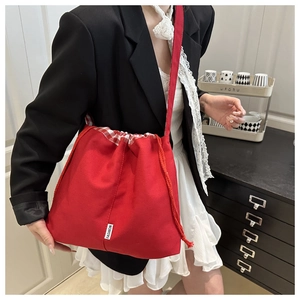 Detail of red canvas tote bag with drawstring closure and fashion label decoration