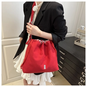 Close-up of red canvas drawstring tote bag featuring a checkered lining and fashion patch