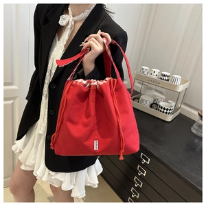 Detailed shot of the red canvas tote with drawstring closure and fashion woven label