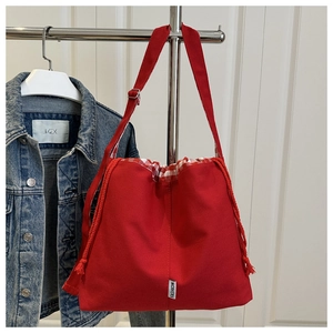 Detail of red canvas tote bag featuring checkered drawstring closure and adjustable strap
