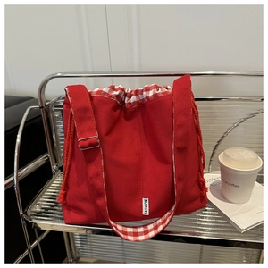 Detail of red canvas tote with drawstring closure, check lining and adjustable strap