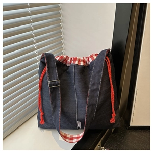 Close-up of denim crossbody bag with red gingham lining and drawstring closure detail
