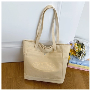 Detail of canvas tote bag showing magnetic clasp closure and spacious side pockets
