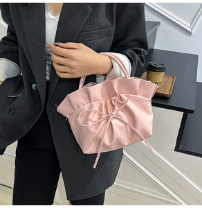 Détail du sac nuage plissé rose avec nœud ruban, porté avec un blazer oversize gris