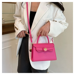 Detailed view of magenta PU handbag showing gold circular twist lock and leather texture