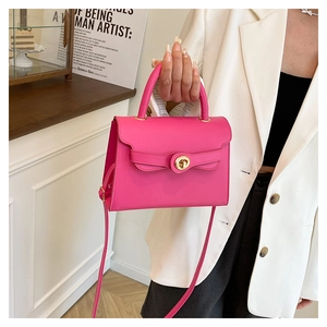 Detail of rose pink leather handbag with gold round twist lock on white blazer
