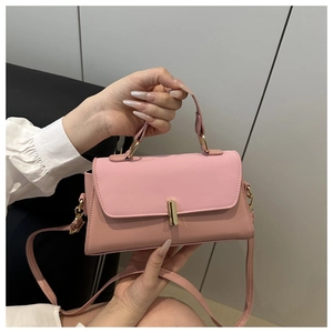 Detailed close-up of pink shoulder bag with gold metal buckle and textured leather flap