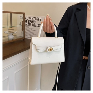 Detail of white Kelly bag with golden round swivel lock and curved top handle