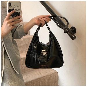 Détail du sac Hobo en cuir verni noir brillant avec logo en métal et fermeture à franges