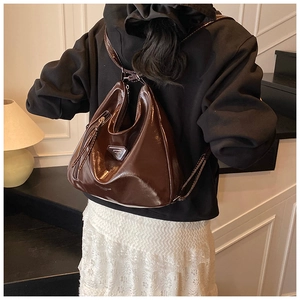 Détail d'un sac à dos en cuir marron foncé brillant avec logo triangulaire argenté au porté