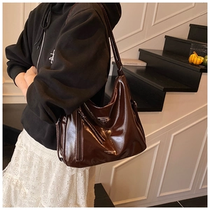 Détail d'un cabas en cuir marron brillant avec logo et poche latérale zippée