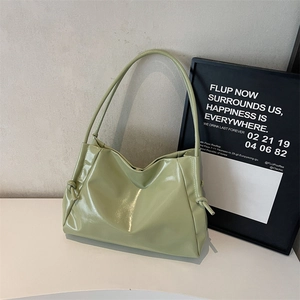 Minimalist light green patent leather tote bag with drawstring knots on a white table