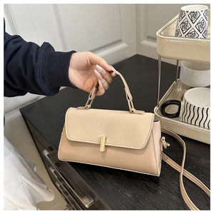 Close-up of beige PU leather handbag showing golden rectangular twist lock and smooth texture