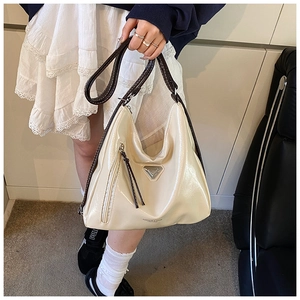 Détail du sac à bandoulière crème avec lanières en cuir marron et plaque métallique