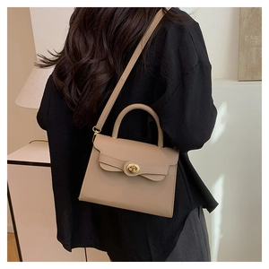 Detail of khaki leather handbag with a wave flap and golden twist lock on a shoulder strap