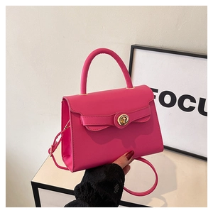 Detailed macro view of the rose red leather handbag with a gold metal turn-lock closure