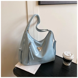 Détail d'un sac hobo bleu clair brillant avec logo triangle en métal et bandoulière