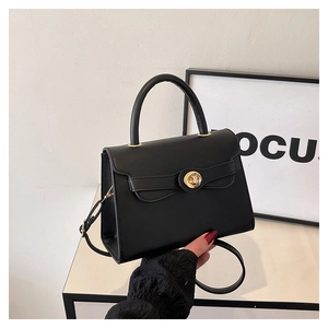 Detailed view of the gold rotary lock and leather texture on a black Kelly bag