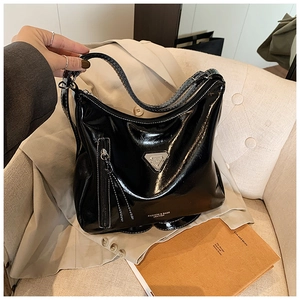 Détail d'un sac cabas noir brillant avec logo métallique et poche zippée pratique