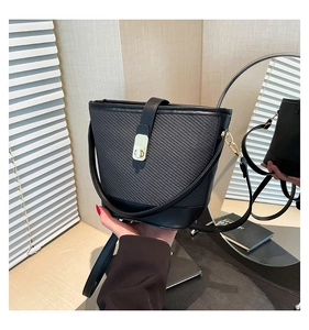 Détail d'un sac seau noir tressé avec fermoir rectangulaire doré et finitions soignées
