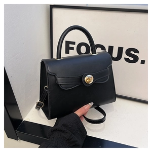 Detail of black matte Kelly bag featuring golden round rotary lock and top handle