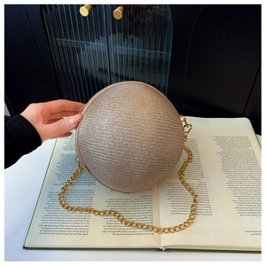 Close-up of champagne gold spherical evening bag with metallic chain and woven texture