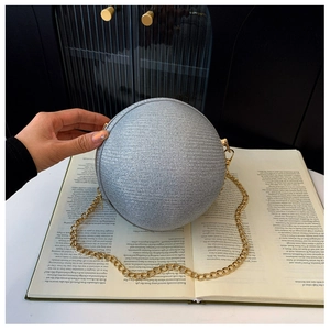 Macro shot of a silver spherical evening bag with textured finish and gold chain handle