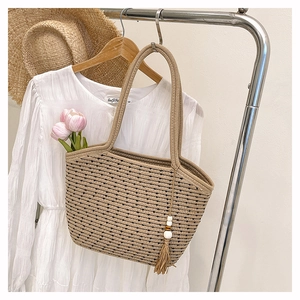 Dettaglio della borsa tote in cotone intrecciato con nappe boho e motivi a righe terra