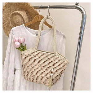 Dettaglio borsa tote intrecciata con motivi a pois marroni e nappa boho con perle di legno
