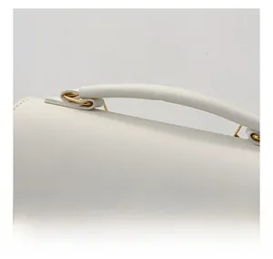 Detail of white lychee textured handbag showing gold metal buckle and sturdy handle