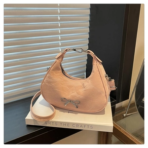 Close-up of pink crinkled leather handbag featuring a silver bow accent and metal zipper