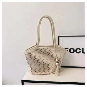 Dettaglio della borsa tote in cotone intrecciata a mano con nappa e trama testurizzata