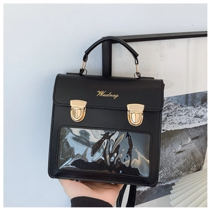 Detail of square black leather crossbody bag featuring a clear window and gold press locks