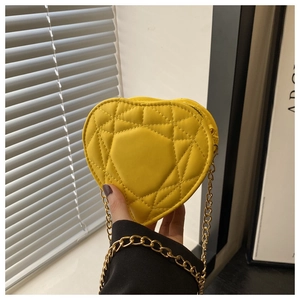 Close-up of mini heart-shaped yellow quilted handbag with elegant gold chain strap