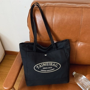 Minimalist black canvas tote bag with shoulder straps and large capacity for daily commute