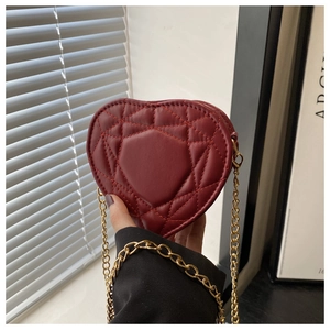 Close-up of heart-shaped burgundy crossbody bag featuring quilted diamond stitching