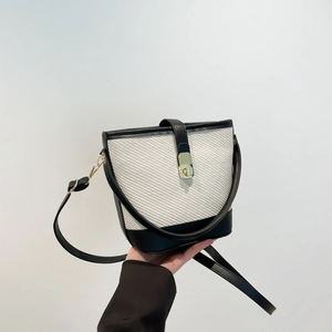 Chic two-tone bucket bag with woven texture, black leather trim, and golden metal lock