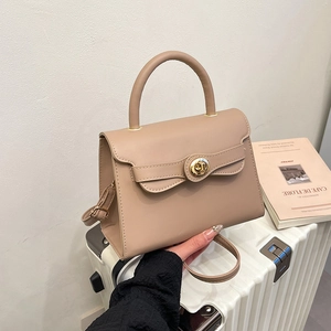 Beige retro kelly-style handbag with gold twist lock and shoulder strap on luggage