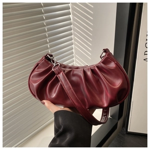 Detail of soft pleated cloud bag in wine red faux leather with silver buckle hardware