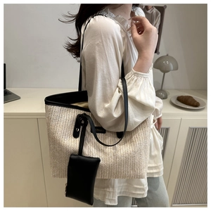 Dettaglio della borsa tote in paglia intrecciata con finiture in pelle nera e astuccio