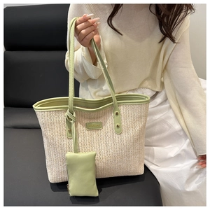 Détail du sac cabas en paille tressée avec bordure en cuir vert et mini pochette
