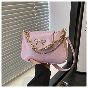 Close-up of pink glossy PU handbag featuring a gold bow buckle and elegant metal chains