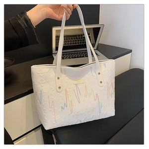 Detail of white tote bag with colorful embroidery and quilted texture on PU leather