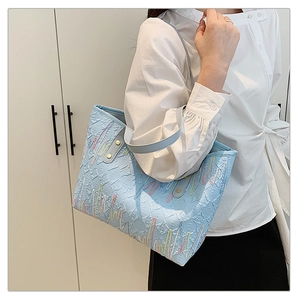 Détail du sac cabas bleu clair avec broderies colorées et gaufrage texturé élégant