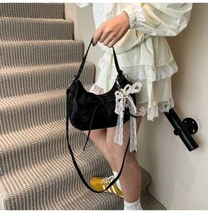 Detail of black bow hobo bag with lace pearl pendant shown in an indoor setting