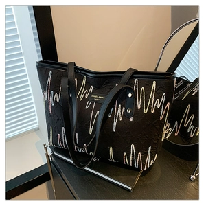 Détail de broderie ondulée colorée sur le sac cabas noir avec étiquette de marque