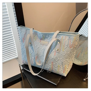 Détail du sac cabas bleu clair avec texture plissée et lignes de broderie colorées