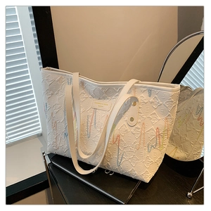 Détail du sac cabas blanc avec texture carrée gaufrée et coutures colorées en zigzag