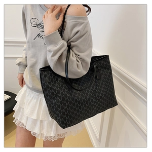 Detail of a large black tote bag with M-letter jacquard pattern on a fashion model